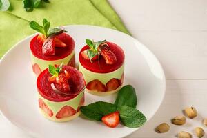 Dessert - - Süss Kuchen mit Erdbeere auf ein Teller mit frisch Minze und Pistazien foto