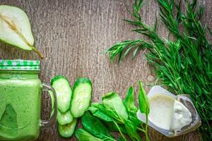 gesund Grün Smoothie mit Spinat im ein Becher gegen auf hölzern Hintergrund foto