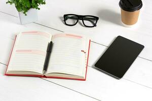 stilvoll minimalistisch Arbeitsplatz mit Tablette und Notizbuch und Brille im eben legen Stil. Weiß Hintergrund. foto