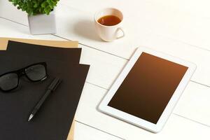 modern Arbeitsplatz mit Digital Tablette Computer und Handy, Mobiltelefon Telefon, Tasse von Kaffee, Stift und leeren Blatt von Papier. foto