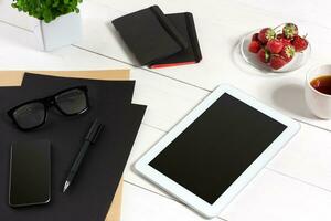 modern Arbeitsplatz mit Digital Tablette Computer und Handy, Mobiltelefon Telefon, Tasse von Kaffee, Stift und leeren Blatt von Papier. foto