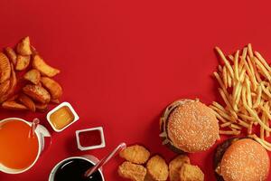 schnell Essen Gericht oben Sicht. Fleisch Burger, Kartoffel Chips und Glas von trinken auf rot Hintergrund. wegbringen Komposition. foto