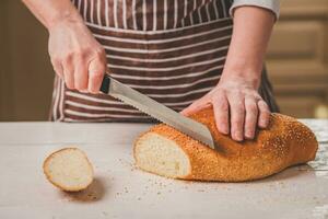 Frau Schneiden Brot auf hölzern Tafel. Backhaus. Brot Produktion. foto