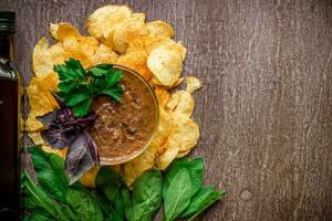 Kartoffel Chips mit Eintauchen Soße auf ein hölzern Tisch. ungesund Essen auf ein hölzern Hintergrund. foto