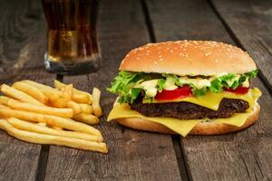 schnell Lebensmittel. Cheeseburger und Französisch Fritten auf ein hölzern Hintergrund foto