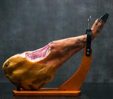 ganze Mittelmeer traditionell Jamon auf ein hölzern Stand mit ein Messer lehnen auf ein Tisch. dunkel Bild foto