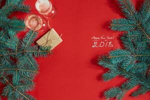 zwei Brille von Champagner mit Weihnachten Baum Ast und klein Geschenk auf ein rot Hintergrund foto