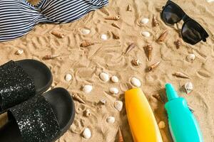 Sommer- Bikini und Zubehör stilvoll Strand Satz, Strand Bikini Sommer- Outfit und Meer Sand wie Hintergrund, oben Sicht, Konzept foto