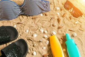 Sommer- Bikini und Zubehör stilvoll Strand Satz, Strand Bikini Sommer- Outfit und Meer Sand wie Hintergrund, oben Sicht, Konzept foto