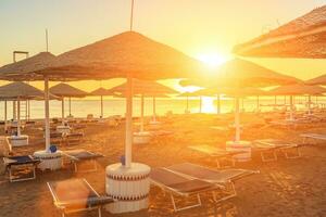 Strand mit Deck Stühle und Sonnenschirm während schön Sonnenaufgang foto