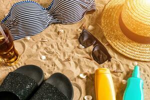 Sommer- Bikini und Zubehör stilvoll Strand Satz, Strand Bikini Sommer- Outfit und Meer Sand wie Hintergrund, oben Sicht, Konzept foto