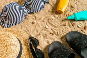 Sommer- Bikini und Zubehör stilvoll Strand Satz, Strand Bikini Sommer- Outfit und Meer Sand wie Hintergrund, oben Sicht, Konzept foto