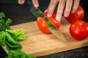 männlich Hände Schneiden Gemüse zum Salat foto