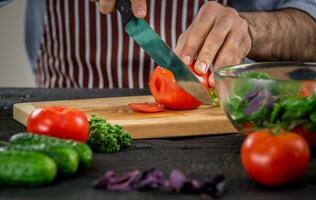 männlich Hände Schneiden Gemüse zum Salat foto