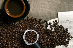 Kaffee Bohnen, Blatt Musik- und Kaffee Tasse auf ein Sackleinen Hintergrund foto