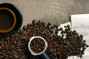 Kaffee Bohnen, Blatt Musik- und Kaffee Tasse auf ein Sackleinen Hintergrund foto
