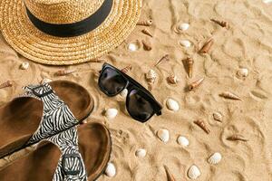 Sommer- Strandkleidung, Flip Flops, Hut, Sonnenbrille und Muscheln auf Sand Strand. foto