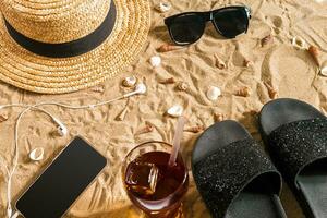 Sommer- Strandkleidung, Flip Flops, Hut, Sonnenbrille und Muscheln auf Sand Strand. foto