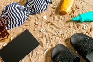 Sommer- Bikini und Zubehör stilvoll Strand Satz, Strand Bikini Sommer- Outfit und Meer Sand wie Hintergrund, oben Sicht, Konzept foto