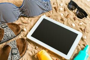 Sommer- Bikini und Zubehör stilvoll Strand Satz, Strand Bikini Sommer- Outfit und Meer Sand wie Hintergrund, oben Sicht, Konzept foto