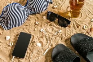 Sommer- Bikini und Zubehör stilvoll Strand Satz, Strand Bikini Sommer- Outfit und Meer Sand wie Hintergrund, oben Sicht, Konzept foto