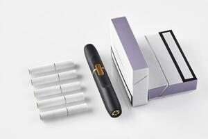 Neu Generation schwarz elektronisch Zigarette, zwei Packungen mit lila Seiten und fünf Hitzestäbe isoliert auf Weiß. Heizung Tabak System. schließen oben foto