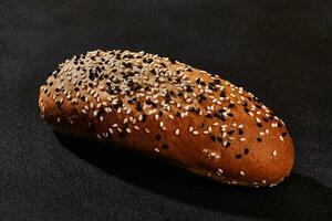 frisch, schmackhaft gebacken Brot bestreut mit schwarz und Weiß Sesam Saat gegen schwarz Hintergrund mit Kopieren Raum. ländlich Küche oder Bäckerei. Nahansicht foto