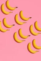 Muster Komposition von ein Paar von Bananen Lügen Nächster zu ein Rosa Hintergrund , oben Aussicht foto