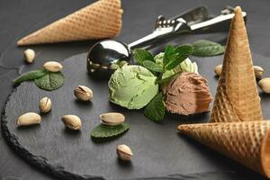 Gourmet Schokolade und Pistazie Eis Sahne serviert auf ein Stein Schiefer Über ein schwarz Hintergrund. foto