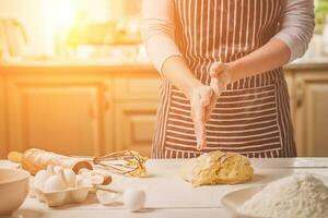 Frau schlagen seine Hände über Teig Nahaufnahme. Bäcker Fertigstellung seine Bäckerei, Shake Mehl von seine Hände, kostenlos Raum zum Text. foto