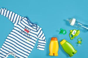 Baby Pflege mit Bad Satz. Nippel, Spielzeug, Kleidung, Shampoo auf Blau Hintergrund oben Aussicht Attrappe, Lehrmodell, Simulation foto