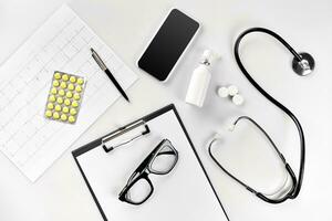 Arzt Büro Schreibtisch mit medizinisch Unterlagen, Diagramme, Brille und Stethoskop. oben Sicht. Kopieren Raum foto