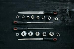 einstellen von Werkzeuge Meißel, Schraubenschlüssel auf schwarz hölzern Hintergrund foto