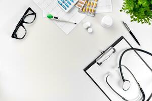 Arzt Büro Schreibtisch mit medizinisch Unterlagen, Diagramme, Brille und Stethoskop. oben Sicht. Kopieren Raum foto