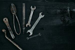 alt, rostig Werkzeuge Lügen auf ein schwarz hölzern Tisch. Hammer, Meißel, Metall Schere, Schlüssel. foto
