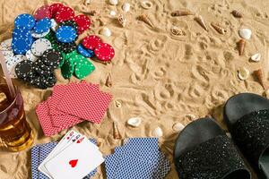 Strandpoker. Chips und Karten auf das Sand. um das Muscheln, Sonnenbrille und Flip Flops. oben Aussicht foto