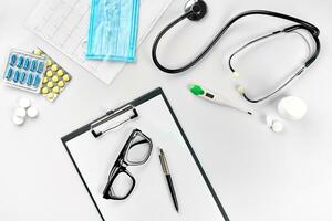 Geschäft einstellen zum Krankenhaus Pillen, Stethoskop, medizinisch Ausrüstung, Hinweis Buch mit Stift und Brille auf Weiß Hintergrund. modern Arzt einstellen auf das Tisch. foto