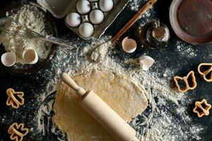 Kochen Teig zum Kekse, Butter, Eier, Kochen Ausrüstung, Mehl auf ein schwarz Tisch. oben Aussicht mit Kopieren Raum, Attrappe, Lehrmodell, Simulation zum Speisekarte, Rezept oder kulinarisch Klassen. Backen Hintergrund. foto