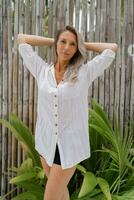 glücklich blond Frau im Weiß Bluse posieren im tropisch Erholungsort. Reisen und Ferien Konzept. foto