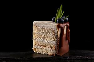 Stück von Kuchen mit Blaubeeren auf ein schwarz Hintergrund, dekoriert mit klein Grün Blätter und frisch Beeren. foto