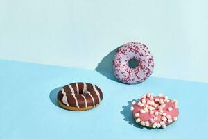 drei bunt Donuts auf ein Blau Hintergrund foto