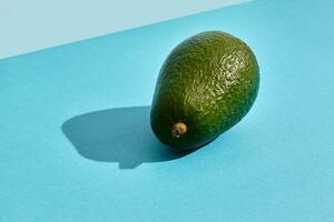 schließen oben hoch Qualität Bild von ganze Avocado, Obst Komposition auf Blau Pastell- foto