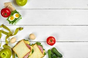 Mittagessen. Sandwiches und frisch Gemüse, Flasche von Wasser und Grün Apfel auf hölzern Tisch. gesund Essen Konzept. oben Aussicht foto