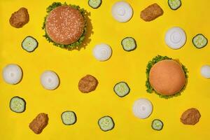 die meisten Beliebt schnell Essen Mahlzeit. Hähnchen Nuggets, Burger mit frisch Gurke und Zwiebeln auf Gelb Hintergrund oben Aussicht foto
