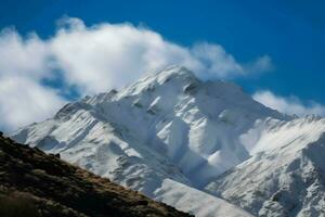 groß schneebedeckt Berg hoch Gipfel unter das Wolken. generieren ai foto