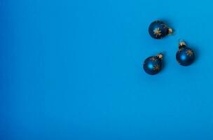 Weihnachten Komposition. drei Blau Bälle mit Gold Sterne auf ein Blau Hintergrund. eben legen, oben Aussicht foto