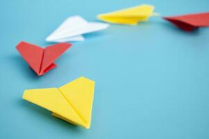 Gelb Papier Flugzeug Origami führen andere Papier Flugzeuge auf Blau Hintergrund. Führung und Kopieren Raum. foto