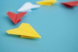 Gelb Papier Flugzeug Origami führen andere Papier Flugzeuge auf Blau Hintergrund. Führung Konzept. foto
