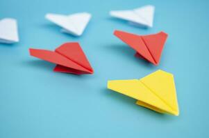 Gelb Papier Flugzeug Origami führen andere Papier Flugzeuge auf Blau Hintergrund. Führung und Kopieren Raum Konzept. foto