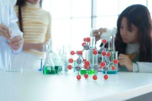 im das Wissenschaft Klassenzimmer, ein asiatisch Kind Wissenschaftler experimentieren mit wissenschaftlich Formeln mit Chemikalien foto